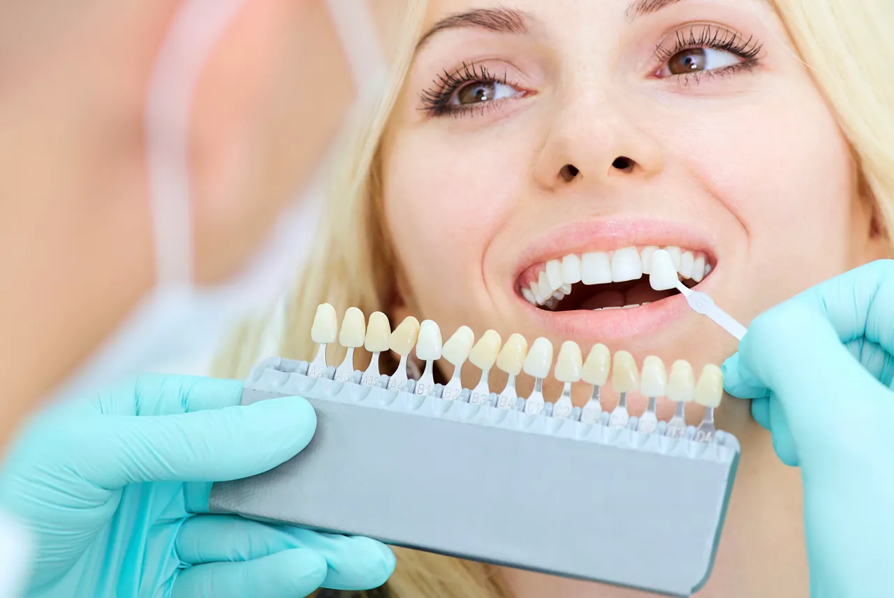 Behandler bespricht während einer Beratung mit einer Patientin die Material- und Farboptionen für Veneers.